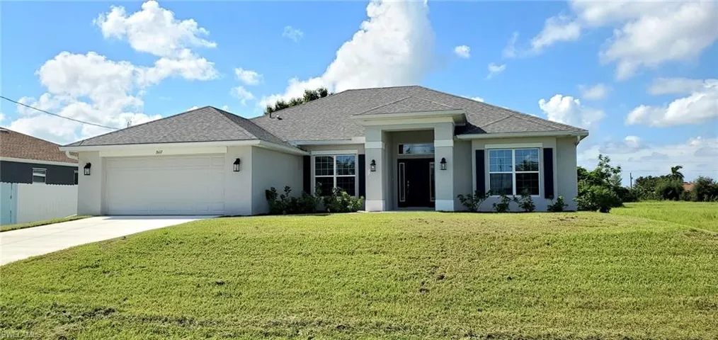 View of front facade featuring a front yard and a garage