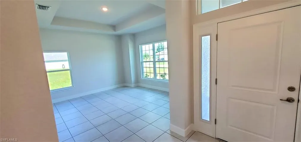 Foyer entrance with a wealth of natural light, a tray ceiling, and light tile patterned flooring