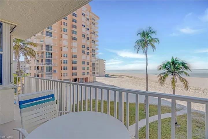 Balcony featuring view of water and beach and outdoor dining space