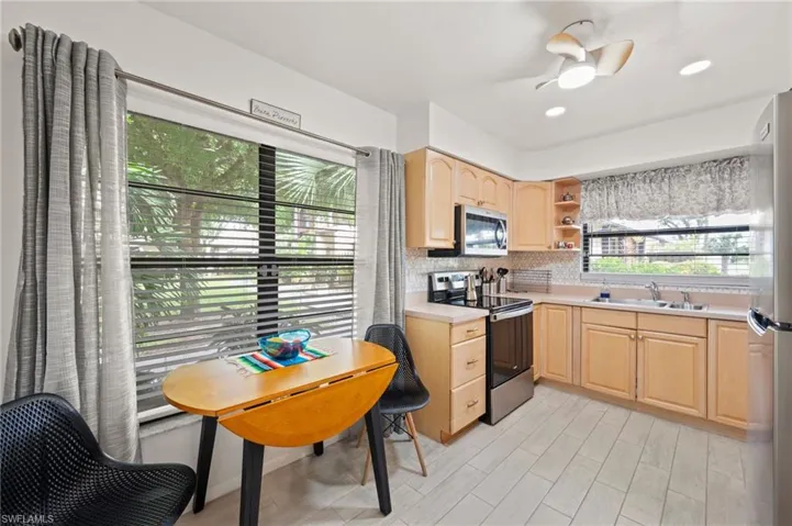 Kitchen with stainless steel appliances, sink, light brown cabinets, ceiling fan, and tasteful backsplash