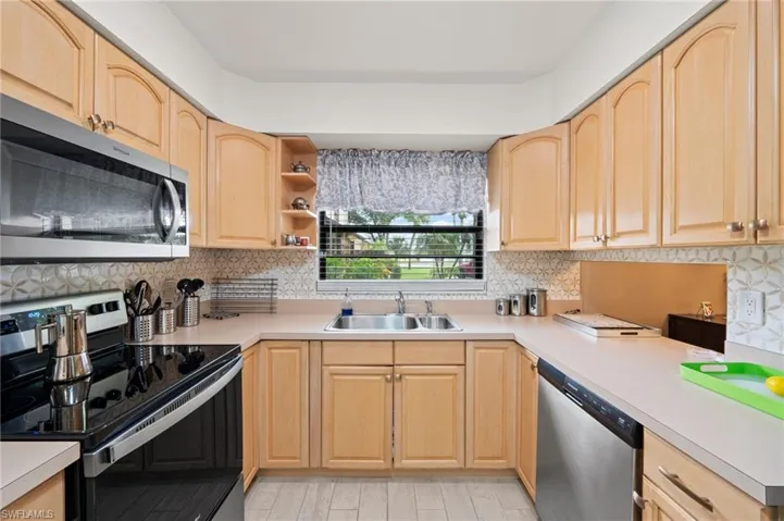 Kitchen featuring light brown cabinetry, stainless steel appliances, and sink