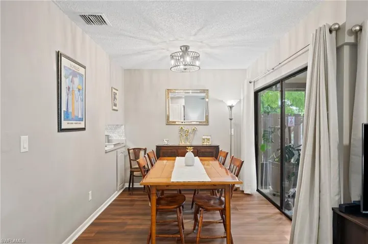 Dining area featuring a textured ceiling, an inviting chandelier, and dark hardwood / wood-style floors