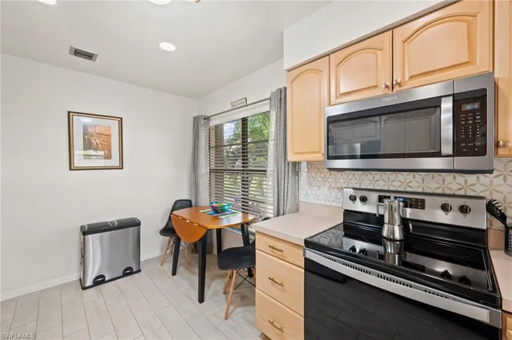 Kitchen featuring light wood-type flooring, light brown cabinetry, backsplash, and stainless steel appliances