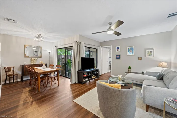 Living room with ceiling fan with notable chandelier, dark hardwood / wood-style flooring, and a textured ceiling