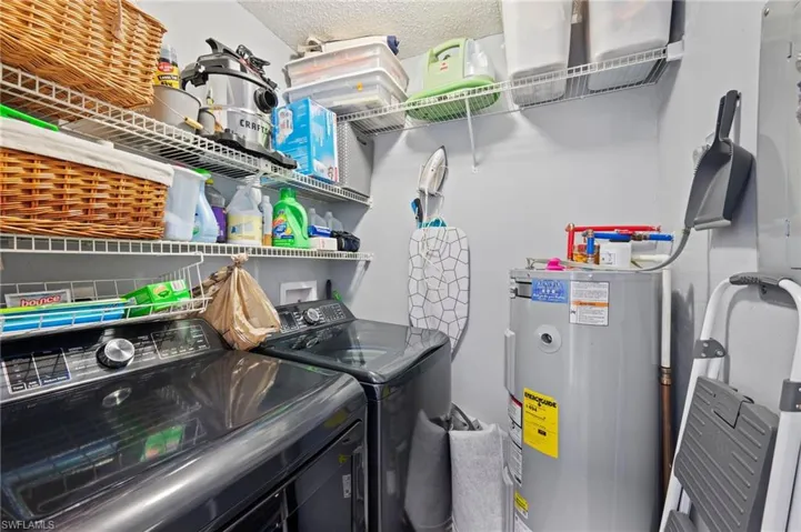 Laundry area featuring a textured ceiling, independent washer and dryer, and water heater