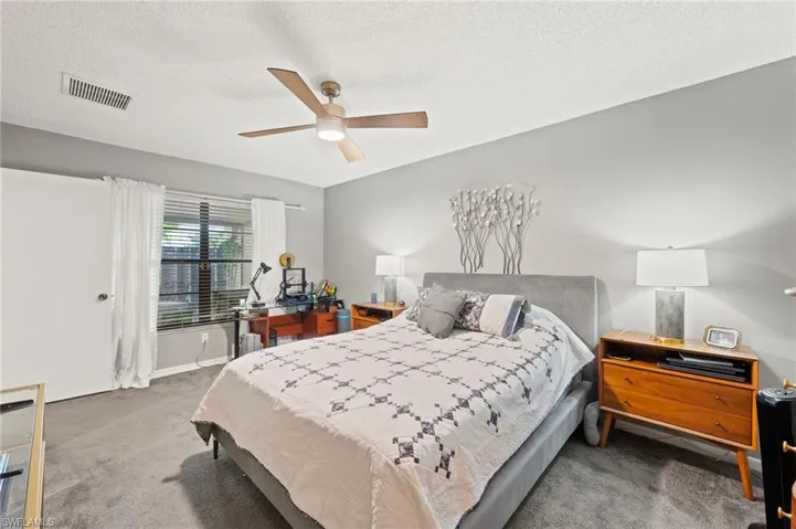 Carpeted bedroom featuring a textured ceiling and ceiling fan