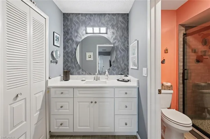Bathroom featuring toilet, vanity, a textured ceiling, hardwood / wood-style flooring, and a shower with shower door