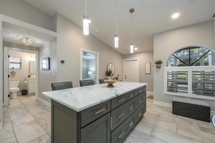 Renovated Kitchen with Quartzite countertops, lofted ceiling, a center island, and pendant lighting