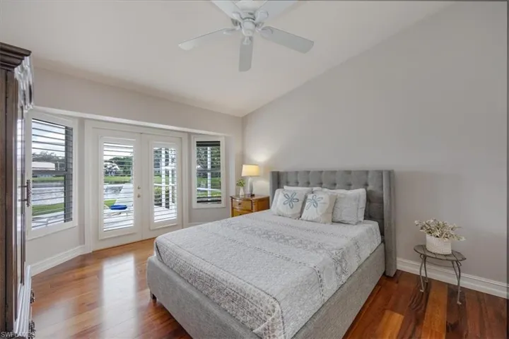Master Bedroom with access to outside, vaulted ceiling, ceiling fan, and cherry hardwood flooring