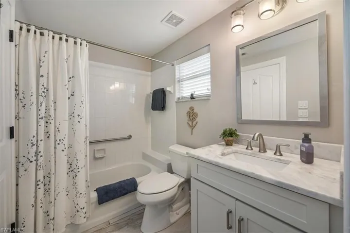 Full guest bathroom with hardwood floors, shower / tub combo