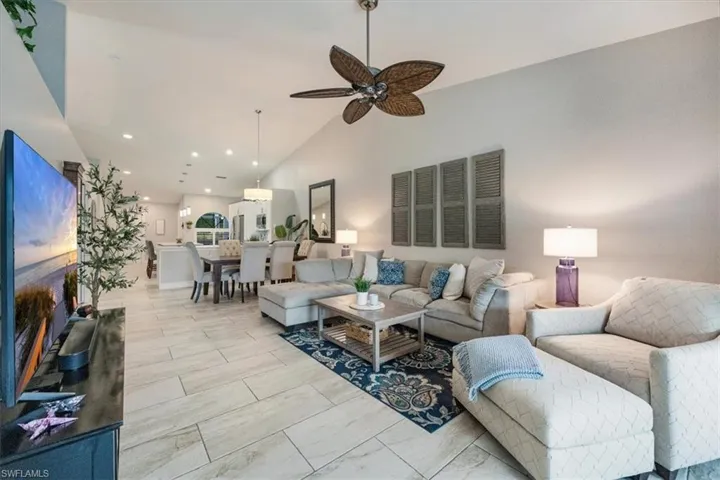 Living room with ceiling fan and high vaulted ceiling