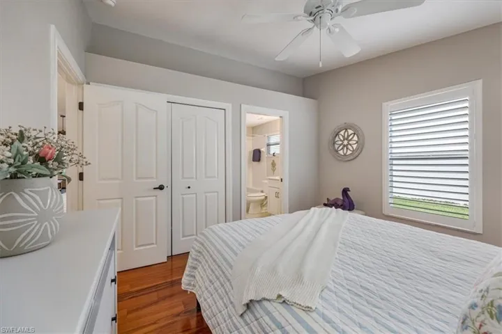 Bedroom 2 with a closet, connected bathroom, ceiling fan, and cherry hardwood floors