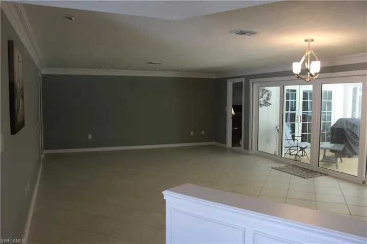 Unfurnished room with ornamental molding, light tile patterned floors, and hanging lights