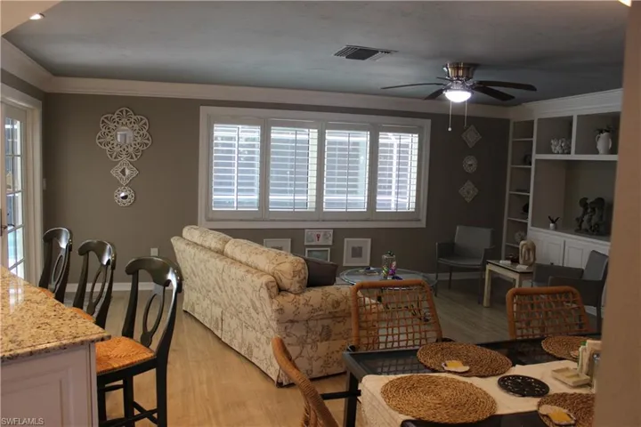 Living room featuring light wood-type flooring, ornamental molding, and ceiling fan