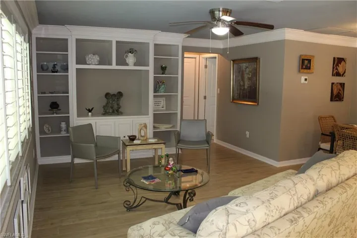Living area featuring a ceiling fan, wood finished floors, and crown molding