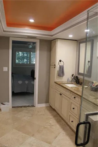 Full bath with ensuite bathroom, vanity, recessed lighting, a tray ceiling, and ornamental molding