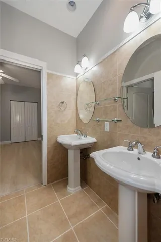 Bathroom featuring tile walls, tile patterned flooring, and ceiling fan