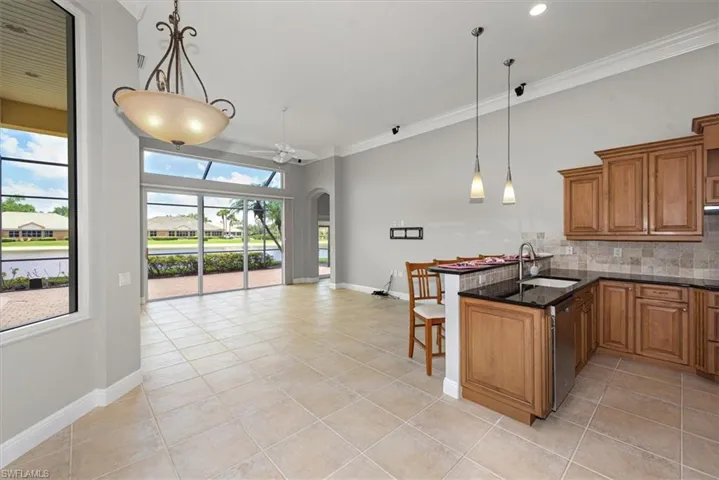Kitchen featuring brown cabinets, light tile patterned floors, a peninsula, arched walkways, and ornamental molding