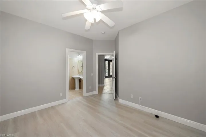 Unfurnished bedroom with light wood finished floors, connected bathroom, and ceiling fan