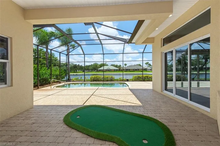 Swimming pool with a patio, a water view, and glass enclosure
