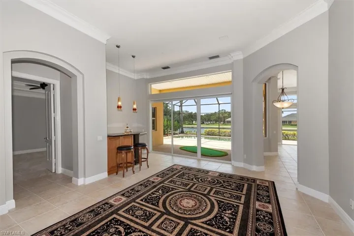 Foyer entrance featuring light tile patterned flooring, arched walkways, crown molding, and plenty of natural light