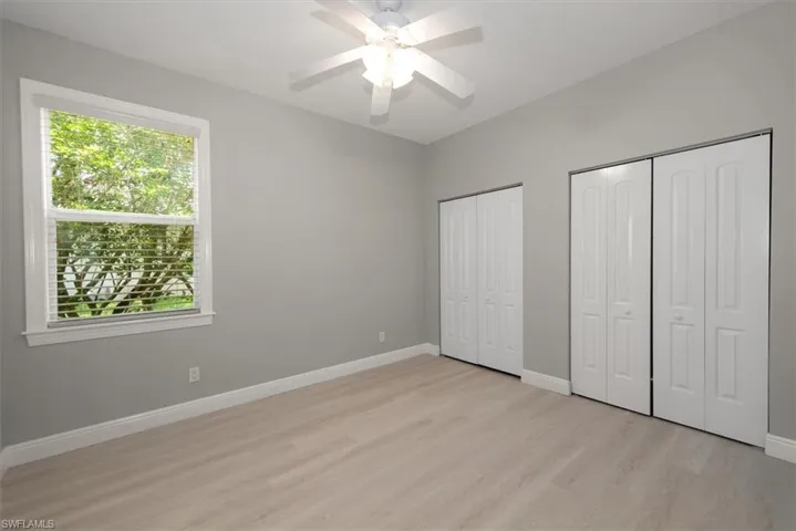 Unfurnished bedroom featuring light wood-style flooring, two closets, and ceiling fan