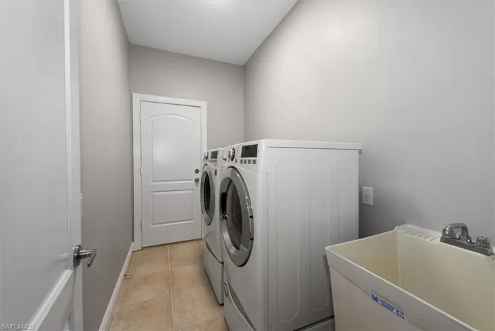 Laundry area with independent washer and dryer and light tile patterned floors
