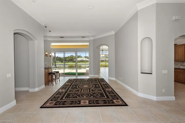 Foyer featuring arched walkways, light tile patterned floors, crown molding, and a water view