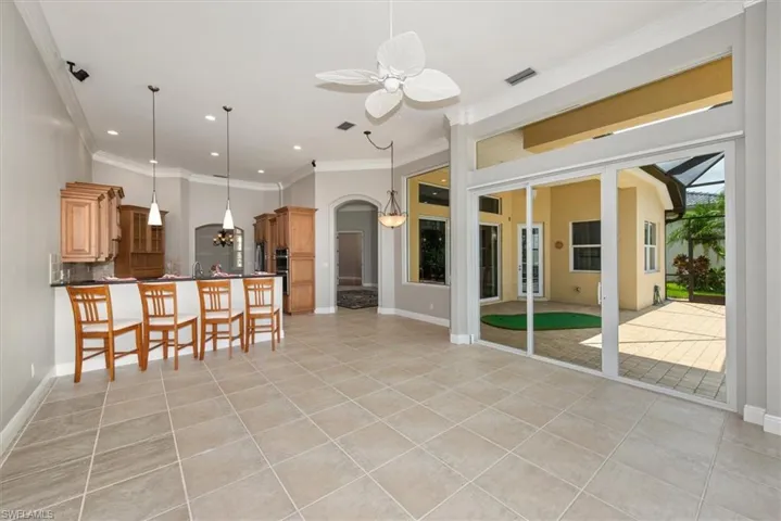 Kitchen with arched walkways, light tile patterned floors, a breakfast bar area, crown molding, and ceiling fan