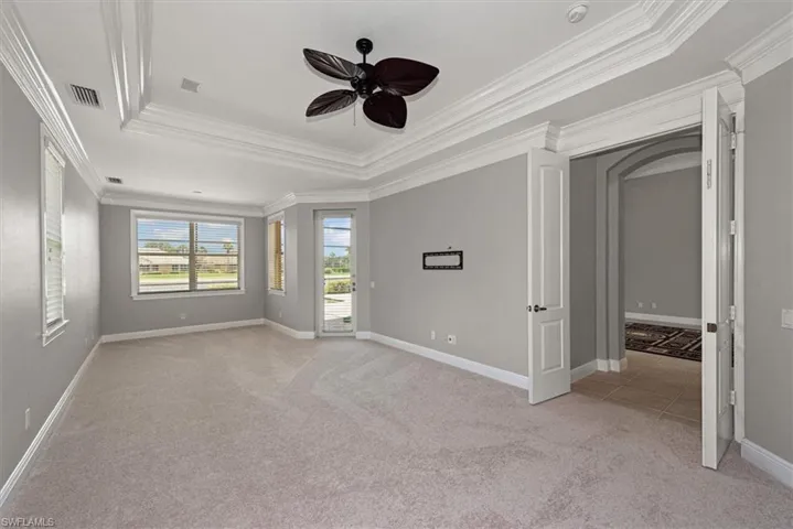 Spare room featuring a tray ceiling, ornamental molding, light carpet, a ceiling fan, and a smoke detector