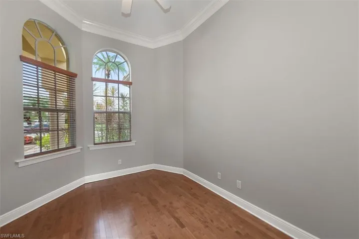 Empty room with dark wood-type flooring, ornamental molding, and a ceiling fan