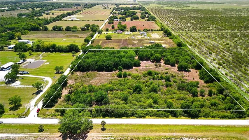 Aerial view of sparsely populated area featuring property parcel outlined and extensive farmland