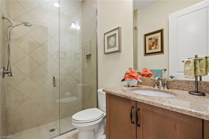Bathroom featuring vanity, toilet, a shower with shower door, and tile patterned flooring