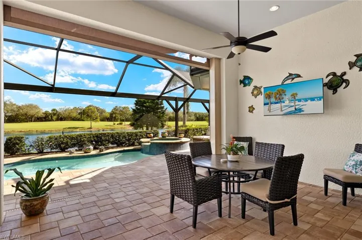 View of patio / terrace featuring a water view, glass enclosure, ceiling fan, and a pool with hot tub