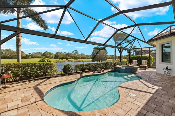 View of pool with an in ground hot tub, a patio, a water view, and glass enclosure
