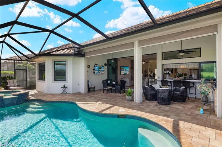 View of swimming pool with ceiling fan, an in ground hot tub, a patio, and a lanai