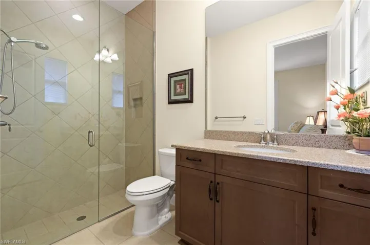 Bathroom featuring vanity, toilet, tile patterned flooring, and a shower with door