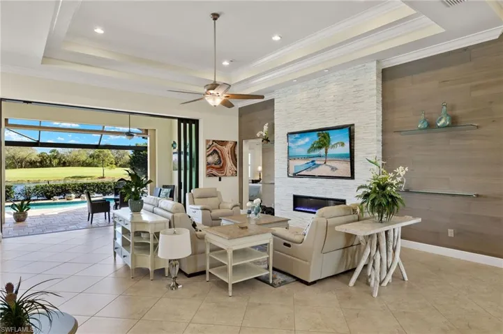 Living room with a fireplace, ornamental molding, a tray ceiling, and light tile patterned floors