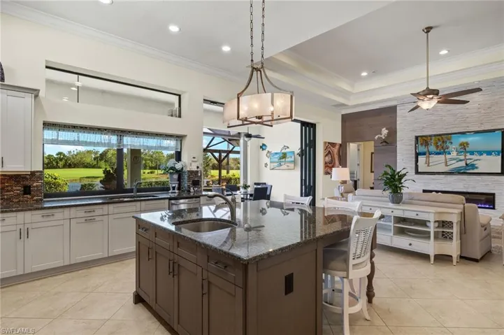 Kitchen with a breakfast bar area, dark stone countertops, sink, and pendant lighting