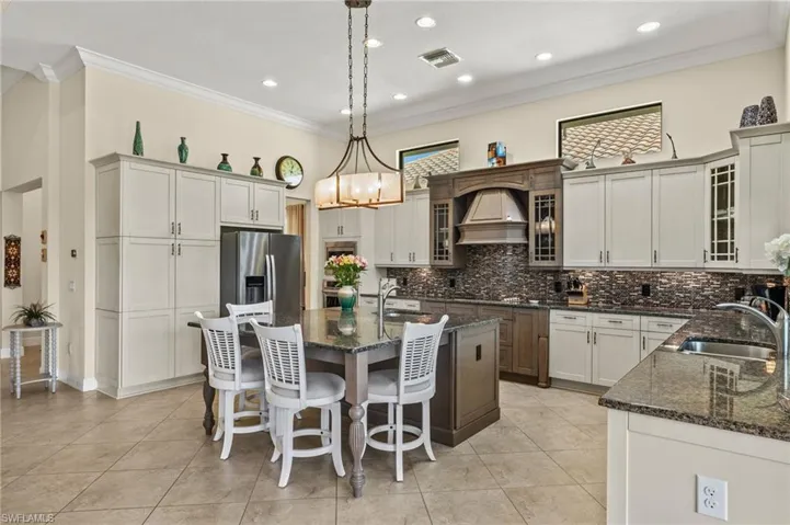 Kitchen featuring sink, hanging light fixtures, a kitchen island with sink, appliances with stainless steel finishes, and crown molding