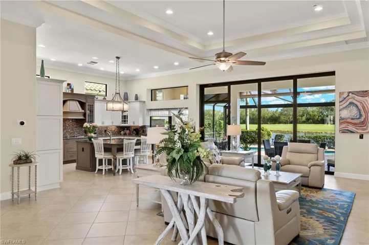 Tiled living room with a tray ceiling, crown molding, and ceiling fan