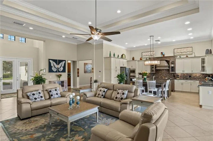 Living room with light tile patterned floors, a towering ceiling, crown molding, and sink