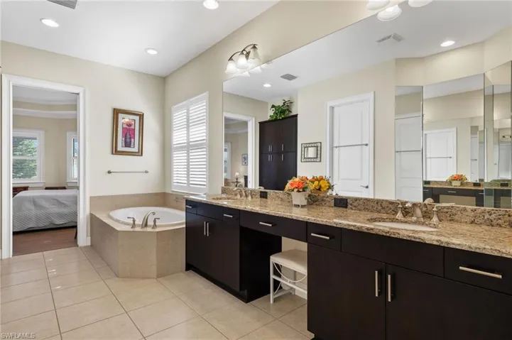 Bathroom with tile patterned flooring, vanity, a relaxing tiled tub, and ornamental molding