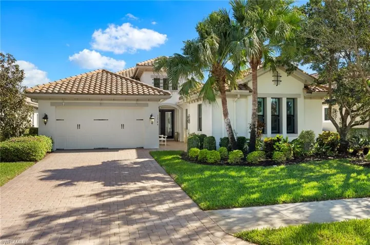 Mediterranean / spanish-style home with a garage and a front lawn