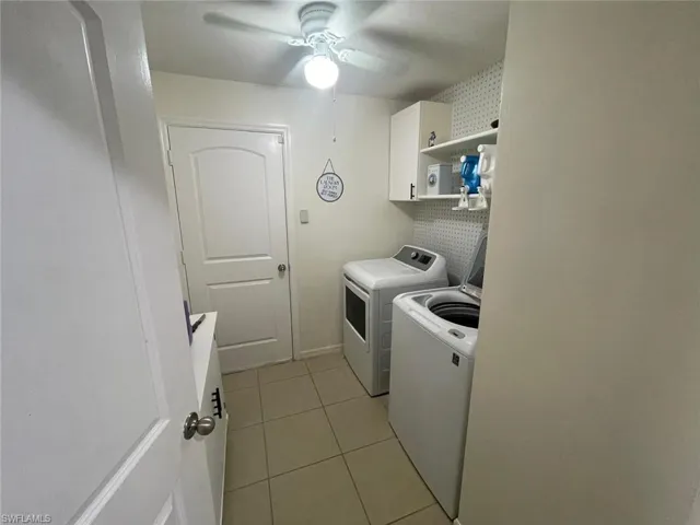 Laundry area with cabinets, light tile patterned flooring, washer and clothes dryer, and ceiling fan
