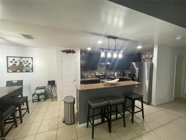 Kitchen featuring a kitchen breakfast bar, tasteful backsplash, stainless steel appliances, and light tile patterned floors