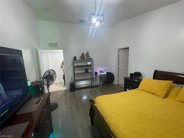 Bedroom featuring a towering ceiling and dark hardwood / wood-style flooring