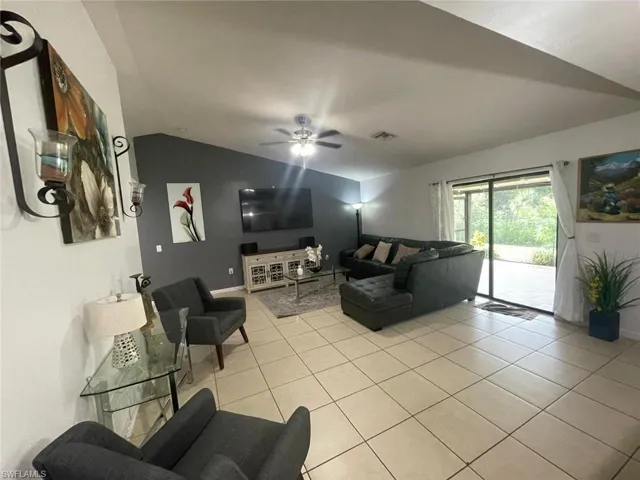 Tiled living room with ceiling fan and vaulted ceiling