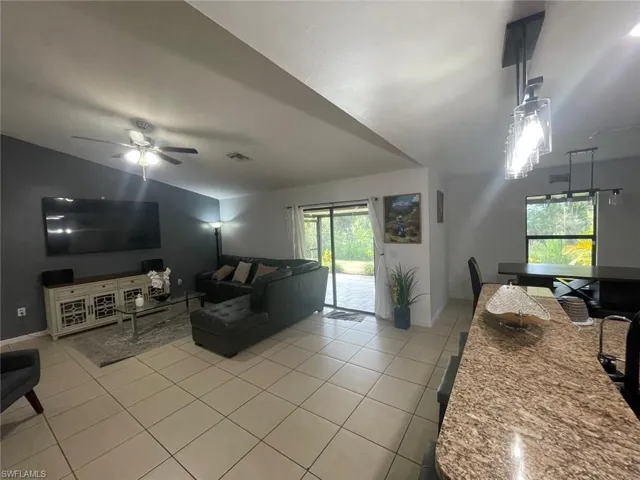 Living room featuring light tile patterned floors, plenty of natural light, and ceiling fan