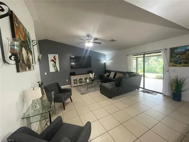 Tiled living room with lofted ceiling and ceiling fan